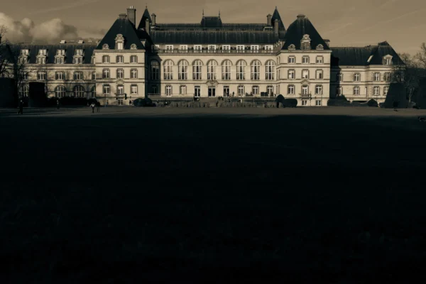 Don · 5662 x 3775 Cette photographie met en scène un imposant bâtiment historique, probablement un palais ou un château, avec une architecture classique et symétrique. Le cadrage est large, centré sur l'édifice, avec un premier plan sombre qui accentue son relief.La lumière, tamisée et contrastée, crée une ambiance dramatique et mystérieuse. Les couleurs dominantes sont les tons sépia et gris, renforçant l'aspect vintage et mélancolique. Le style rappelle une esthétique cinématographique ou photographique ancienne, évoquant une atmosphère à la fois majestueuse et solennelle.