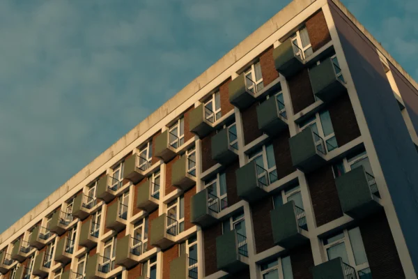 Don · 5993 x 3995 Cette photographie met en scène un immeuble moderne vu en contre-plongée. Le sujet principal est un bâtiment aux balcons en saillie, disposés de manière géométrique.La composition est dynamique, avec un cadrage serré qui accentue la hauteur et la structure architecturale. La lumière, douce et naturelle, semble provenir d’un angle latéral, créant des ombres légères. Les couleurs dominantes sont les tons gris-beige des façades, contrastant avec les balcons noirs et les teintes bleutées du ciel.Le style est épuré et contemporain, évoquant une ambiance urbaine et minimaliste.