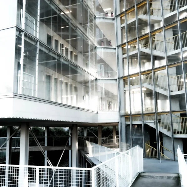 Nathalie F. · 17/01/2026 · 4160 x 4160 Cette photographie montre un bâtiment moderne aux allures résidentielles ou d’hébergement collectif. Le sujet principal est une façade en verre et métal, avec des balcons en saillie et des structures métalliques apparentes.La composition met en valeur les lignes verticales et horizontales, créant un effet géométrique. Le cadrage est serré, centré sur les étages inférieurs et moyens. La lumière, naturelle et diffuse, accentue les contrastes entre les surfaces vitrées et métalliques.Les couleurs dominantes sont le gris métallique, le blanc et le beige, renforçant un style contemporain et minimaliste. L’ambiance est froide et épurée, évoquant une architecture fonctionnelle et moderne.