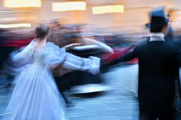 Xavier · 30/10/2025 · 4096 x 2731 Cette photographie capture un couple en mouvement, probablement en train de danser. Le sujet principal est flou, suggérant un effet de vitesse ou de rotation. La composition met en avant leurs silhouettes élégantes, l’un en tenue de soirée blanche et l’autre en costume noir.Le cadrage est serré, centré sur les danseurs. La lumière est douce, créant une ambiance tamisée et chaleureuse. Les couleurs dominantes sont les tons sombres et blancs, renforçant l’élégance et le mouvement. Le style est dynamique, presque artistique, évoquant une ambiance romantique et festive.