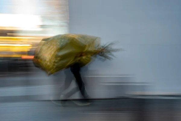 Jean-Marc · 03/01/2026 · 5254 x 3503 Cette photographie capture un sujet flou en mouvement, probablement une personne tenant un sac en plastique transparent. La composition est dynamique, avec un effet de vitesse suggéré par les traits flous. Le cadrage est serré, centré sur le sujet en mouvement devant un fond neutre et légèrement coloré.Les couleurs dominantes sont des tons froids (blanc, gris) avec des éclats de jaune et vert du sac. Le style est artistique et expressif, utilisant le flou pour créer une impression de vitesse et d'énergie. L'ambiance est moderne et urbaine, évoquant le quotidien pressé.