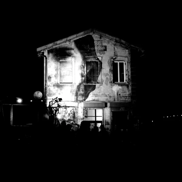 Fabienne · 14/01/2026 · 3016 x 3016 Cette photographie montre une maison en ruine partiellement détruite, sujet principal évident. La composition est centrée sur l'édifice, avec un cadrage serré qui met en valeur son état de délabrement. La lumière, faible et contrastée, provient probablement d'une source artificielle, créant des ombres marquées et soulignant les dégâts.En noir et blanc, les tons dominants varient du blanc cassé au noir profond. Le style est documentaire et réaliste, évoquant une ambiance dramatique et mélancolique, renforcée par l'obscurité nocturne et l'abandon apparent du lieu.