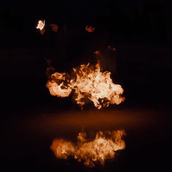 Frédéric · 1680 x 1680 Cette photographie capture une **explosion enflammée** comme sujet principal. La **composition** est épurée, centrée sur la boule de feu flottante, reflétée dans une surface liquide en bas de l'image.Le **cadrage** est serré, isolant l'élément dynamique. La **lumière** est intense et contrastée, avec des ombres profondes. Les **couleurs dominantes** sont des **tons chauds** (oranges, jaunes) sur fond noir, créant un fort contraste.Le style est **dramatique et cinétique**, évoquant une ambiance **spectaculaire et intense**, presque surnaturelle. L'effet de miroir ajoute une dimension mystérieuse.