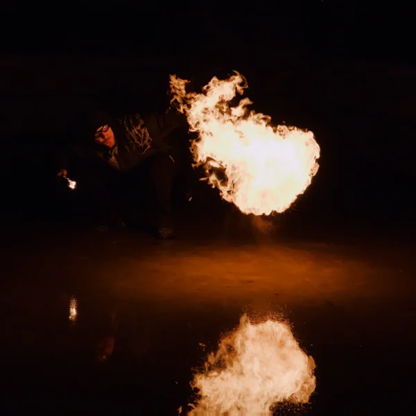 Frédéric · 25/01/2026 · 1680 x 1680 Cette photographie capture une **explosion ou une flamme intense** dans l'obscurité. Le **sujet principal** est la masse lumineuse orange-jaune, contrastant avec le fond noir.La **composition** est épurée, centrée sur la flamme, avec une **symétrie** suggérée par son reflet sur une surface liquide en bas. Le **cadrage** est serré, isolant l’élément dynamique.Les **couleurs dominantes** sont des tons chauds (orange, jaune) sur un arrière-plan sombre. Le **style** est réaliste et brut, évoquant une scène dramatique. L’**ambiance** est **spectaculaire et intense**, presque menaçante, avec une forte émotion visuelle.