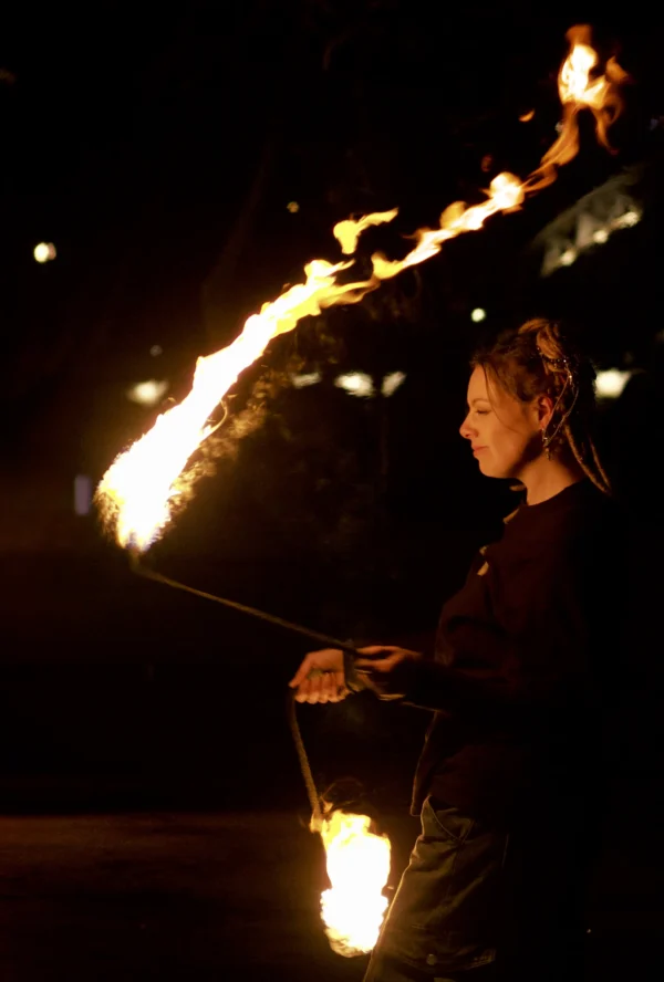 Thomas · 24/01/2026 · 1895 x 2806 Cette photographie met en scène une personne manipulant des torches enflammées, sujet principal captivant. La composition est dynamique, avec des lignes courbes formées par les flammes qui guident le regard. Le cadrage serré isole le sujet dans une ambiance nocturne.Les couleurs dominantes sont les teintes chaudes des flammes (oranges et jaunes) contrastant avec l'obscurité ambiante. Le style est artistique et dramatique, évoquant une scène de spectacle ou rituel. L’ambiance est intense, presque mystique, grâce à la lumière vive et aux jeux d'ombres.