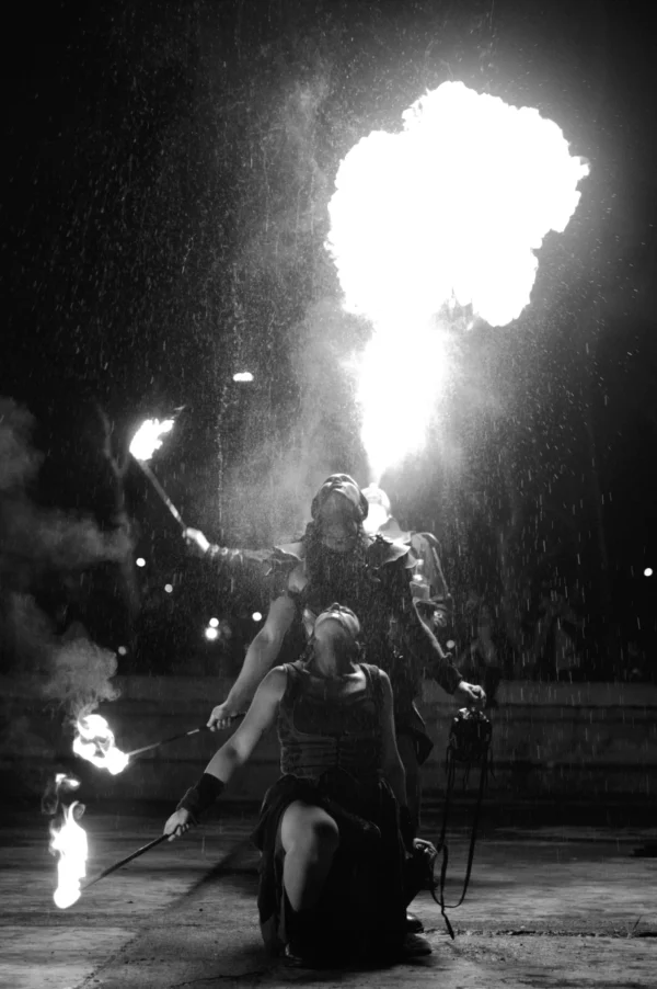 Thomas · 24/01/2026 · 2048 x 3080 Cette photographie en noir et blanc met en scène un artiste manipulant des torches enflammées, créant une explosion de feu spectaculaire. Le sujet principal est le performeur, en position accroupie, entouré de flammes.La composition est dynamique, centrée sur l'action intense. Le cadrage serré isole le sujet, renforçant l'impact visuel. Les jeux de lumière, contrastés et dramatiques, soulignent les éclats de feu et les ombres. L'absence de couleurs accentue les contrastes lumineux, ajoutant une ambiance théâtrale et mystérieuse. Le style rappelle le spectacle vivant, mêlant danger et art.