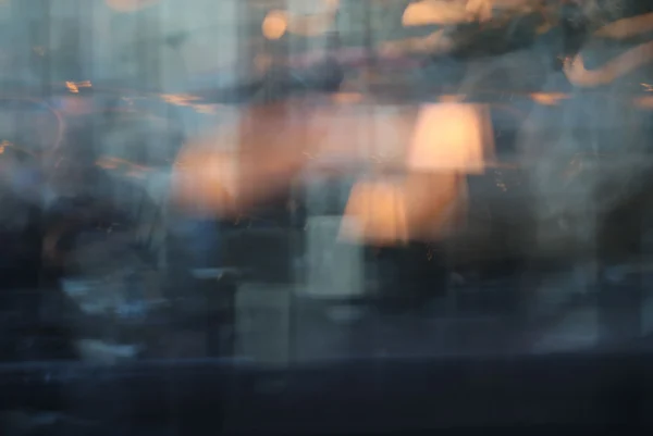 Laurence · 3472 x 2320 Cette photographie capture une scène floue et abstraite, probablement vue à travers une vitre embuée ou mouillée. Le **sujet principal** est indéfinissable en raison du flou, mais on devine des silhouettes et des lumières urbaines.La **composition** est désordonnée, avec des formes indistinctes et des éclats lumineux. Le **cadrage** est serré, centré sur une portion de la vitre.Les **couleurs dominantes** sont des teintes froides (bleus, gris) contrastées par des **lueurs chaudes** (jaunes, oranges). Le **style** est impressionniste et flou, évoquant une ambiance **onirique et mélancolique**, presque nocturne.