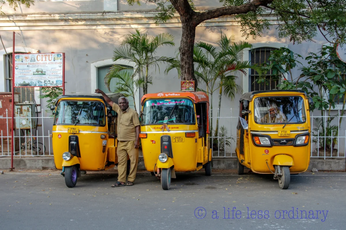 Cédric · 13/01/2018 · 4882 x 3254 Cette photographie met en scène trois **tuk-tuks jaunes** alignés, sujets principaux de l'image. La composition est symétrique, avec un cadrage serré sur les véhicules et leur conducteur.La lumière est naturelle et semble douce, éclairant bien la scène sans ombres marquées. Les couleurs dominantes sont le **jaune vif** des tuk-tuks et des éléments urbains, contrastant avec les tons neutres du bâtiment et du sol.Le style est documentaire et réaliste, capturant une scène de vie quotidienne. L’ambiance est **urbaine et animée**, reflétant un environnement dynamique et coloré.