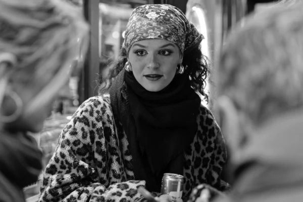 Mickaël · 10/01/2026 · 4680 x 3124 Cette photographie en noir et blanc met en scène une femme comme sujet principal, vêtue d’un manteau à motifs léopard et d’un foulard sur la tête. La composition montre une ambiance intime, probablement dans un lieu public comme un train ou un café. Le cadrage serré met l’accent sur son visage expressif et son regard intense.La lumière est douce, créant des contrastes subtils. Les couleurs, bien que monochromes, suggèrent des tons clairs et sombres typiques du noir et blanc. Le style rappelle le cinéma classique ou documentaire, avec une ambiance à la fois réaliste et légèrement dramatique.