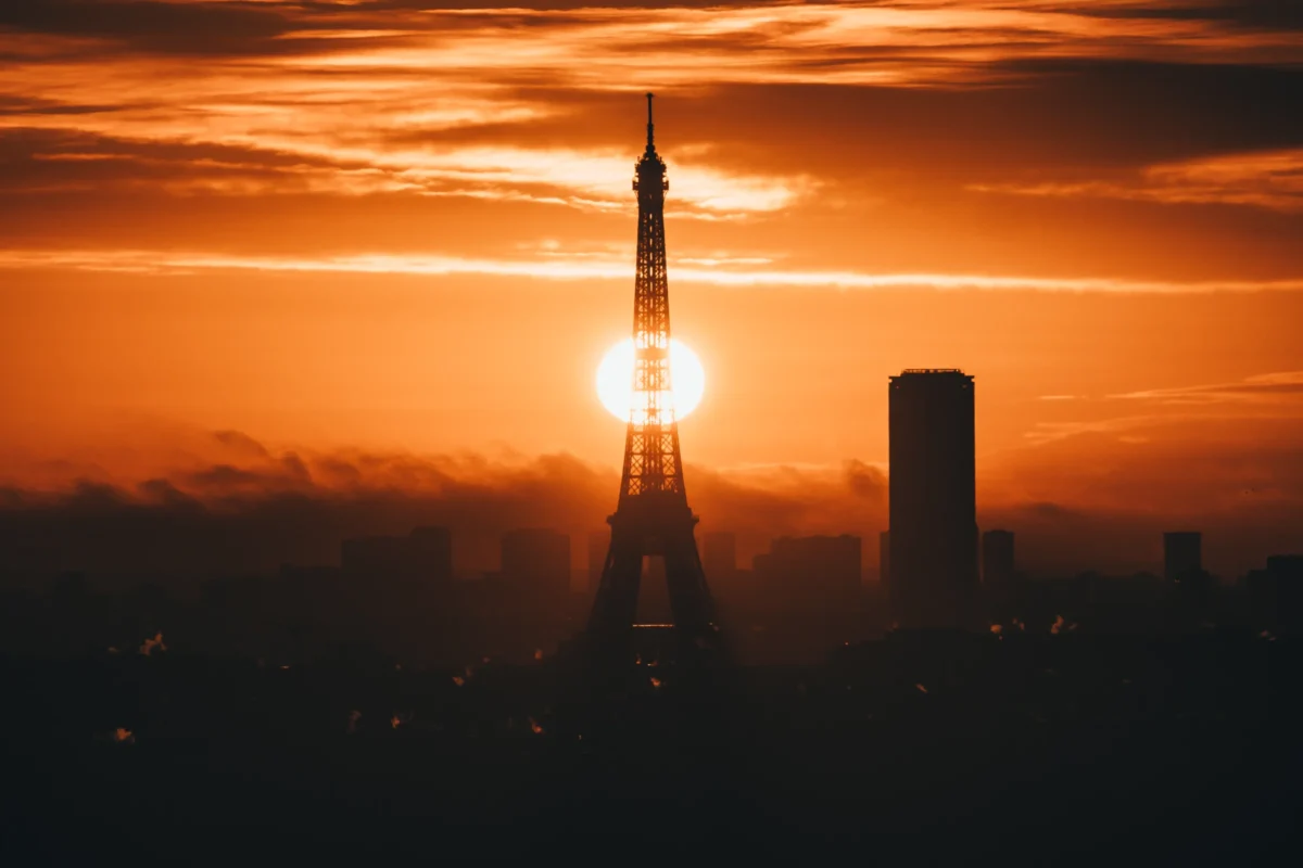 Daniel · 13/12/2020 · 4853 x 3235 Cette photographie met en scène un **monument emblématique** (la tour Eiffel) partiellement visible, avec une **roquette** en silhouette devant elle. La **composition** joue sur les contrastes entre les formes architecturales et spatiales. Le **cadrage** est serré, centré sur l’horizon où le soleil se couche.La **lumière** est douce et dorée, créant une ambiance chaleureuse. Les **couleurs dominantes** sont les tons chauds (oranges, rouges) du coucher de soleil, contrastant avec le noir profond du ciel et des structures. Le **style** est épuré et dramatique, évoquant une **ambiance onirique et mélancolique**, mêlant nature et technologie.