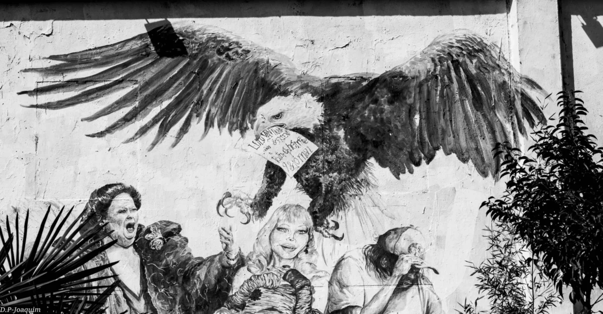 Pierre-Joaquim · 30/03/2015 · 6000 x 3125 Cette photographie en noir et blanc représente un mural ou une fresque. Le sujet principal est un aigle aux ailes déployées dominant des figures humaines en contrebas, suggérant une scène de pouvoir ou de menace. La composition est dynamique, avec un cadrage serré sur les détails expressifs des personnages et de l'oiseau.La lumière semble naturelle, mettant en valeur les contrastes. Les couleurs, absentes en raison du filtre noir et blanc, laisseraient probablement place à des tons sombres et contrastés. Le style évoque l’art mural engagé, avec une ambiance dramatique et symbolique, renforcée par les expressions intenses des personnages.