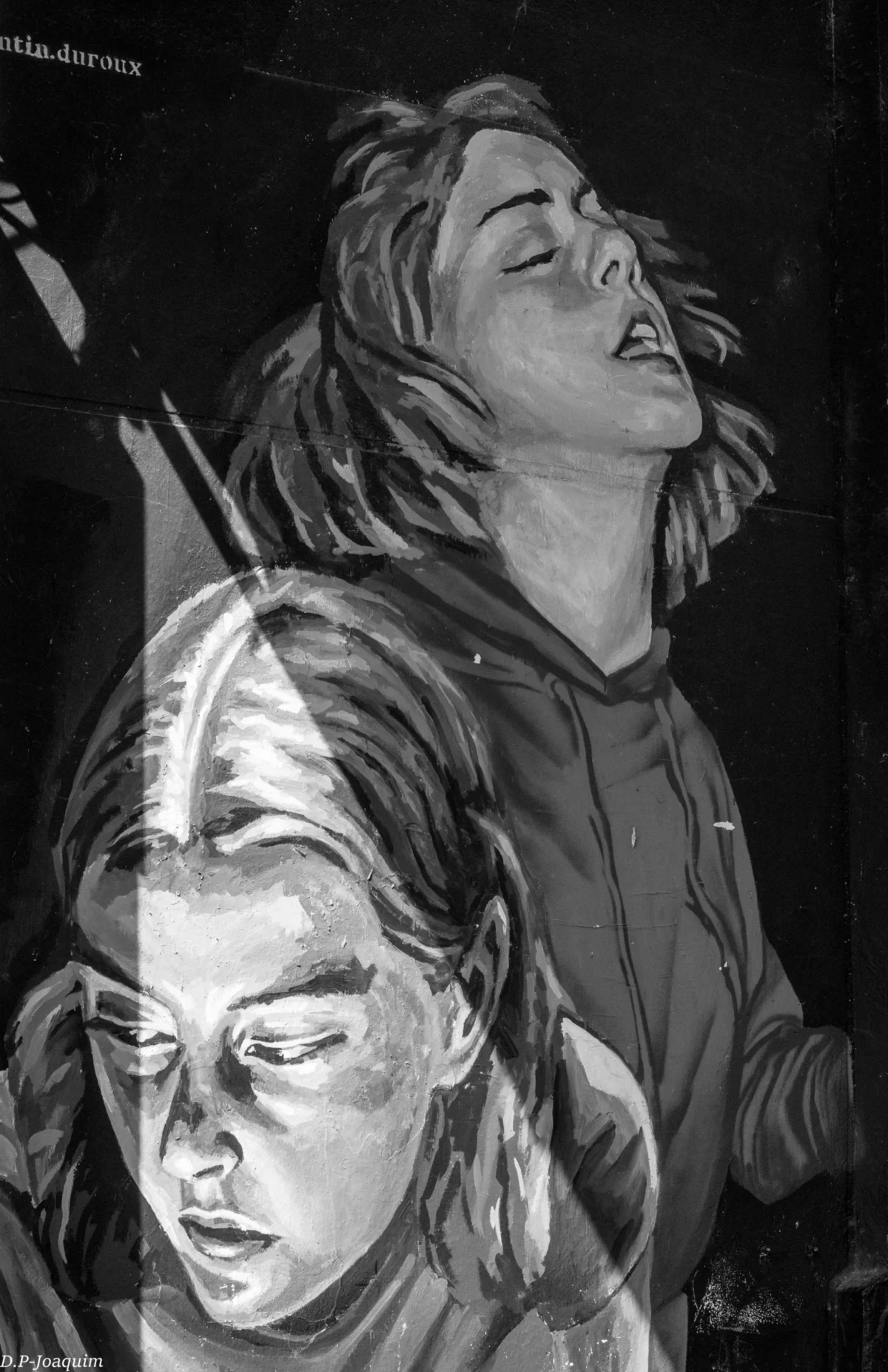 Pierre-Joaquim · 30/03/2015 · 3882 x 6000 Cette image en noir et blanc représente deux visages féminins superposés, formant un seul sujet principal. La composition joue sur la répétition et la fusion des traits, créant une impression de dualité.Le cadrage est serré, centré sur les visages. La lumière est douce, avec des contrastes marqués qui accentuent les ombres et les contours.Les couleurs dominantes sont les nuances de gris, renforçant l’aspect dramatique.Le style rappelle le dessin ou une gravure, avec des traits expressifs. L’ambiance est à la fois mélancolique et intense, évoquant une émotion profonde et mystérieuse.