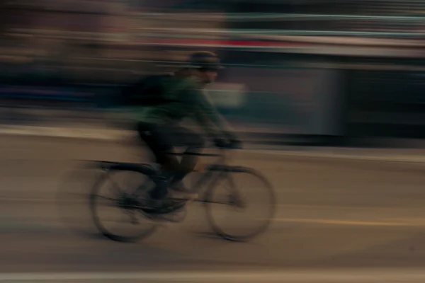 Don · 5631 x 3754 Cette photographie capture un cycliste en mouvement, sujet principal flou suggérant une vitesse. La composition est dynamique, avec un cadrage serré sur le vélo et le cycliste, centré dans l'image. La lumière semble naturelle mais tamisée, créant une ambiance nocturne ou crépusculaire. Les couleurs dominantes sont des tons sombres et neutres, avec des touches de vert et de gris. Le style est réaliste et spontané, évoquant un effet de vitesse par le flou de mouvement. L'ambiance est à la fois urbaine et intimiste, transmettant une sensation de rapidité et de liberté.