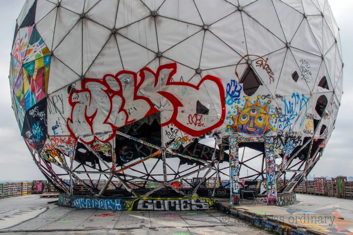 Cédric · 26/05/2017 · 4806 x 3203 Cette photographie montre une structure géodésique recouverte de graffitis. Le sujet principal est un immense dôme partiellement tagué, avec des couleurs vives et contrastées, notamment du rouge et du noir.La composition met en valeur les tags au premier plan, tandis que le cadrage inclut aussi des éléments architecturaux en arrière-plan. La lumière semble naturelle, mais diffuse, créant des ombres douces. Les couleurs dominantes sont vives et saturées, typiques du street art.Le style est urbain et déstructuré, évoquant une ambiance de négligence et de créativité anarchique, renforcée par l’aspect abandonné du lieu.