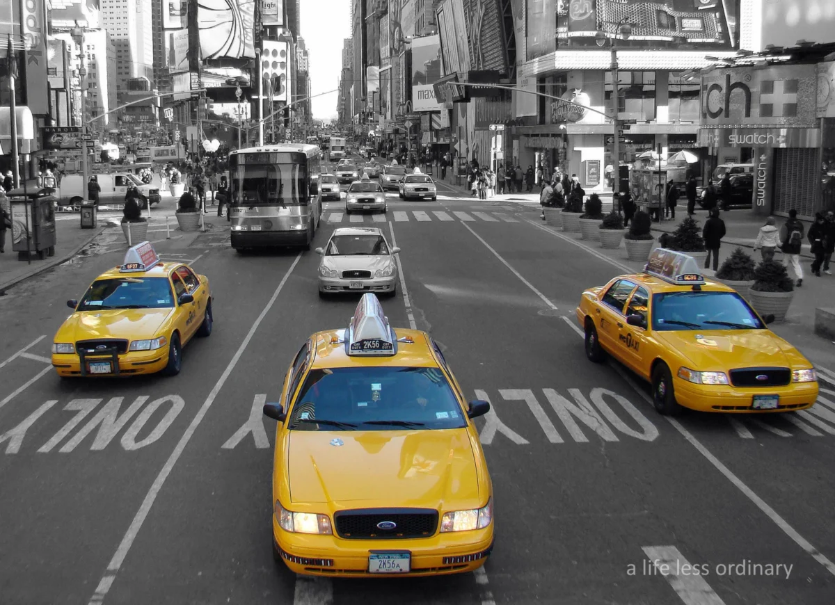 Cédric · 15/02/2010 · 2632 x 1908 Cette photographie capture des **taxis jaunes new-yorkais** comme sujet principal. La composition montre une vue aérienne d’une rue animée, avec les taxis alignés au premier plan et des bâtiments emblématiques en arrière-plan.Le cadrage est large, incluant plusieurs véhicules et une partie de Times Square. La lumière est naturelle, bien répartie, avec une ambiance urbaine dynamique. Les **couleurs dominantes** sont le jaune vif des taxis, contrastant avec les tons gris et blancs des bâtiments.Le style est documentaire, reflétant la vie trépidante de la ville. L’ambiance est **énergique et typiquement new-yorkaise**.