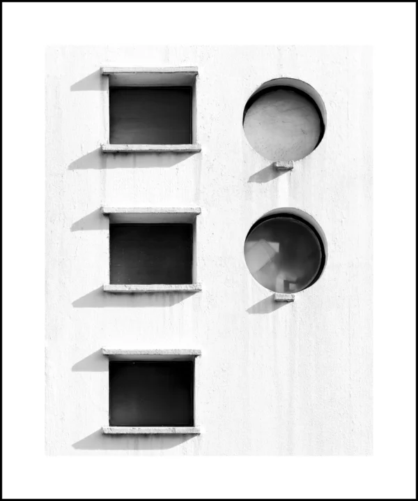 Thierry · 21/02/2026 · 3912 x 4680 Cette photographie met en scène une installation minimaliste composée de trois cadres rectangulaires vides et deux disques circulaires suspendus, alignés verticalement.La composition est épurée et géométrique, avec un cadrage serré. La lumière, douce et uniforme, crée des contrastes nets entre les formes et l'arrière-plan blanc. Les couleurs dominantes sont le noir (cadres et disques) et le blanc, renforçant l’aspect monochrome et abstrait.Le style rappelle l’art moderne ou contemporain, évoquant une ambiance sobre, presque méditative, axée sur la simplicité et l’équilibre visuel.