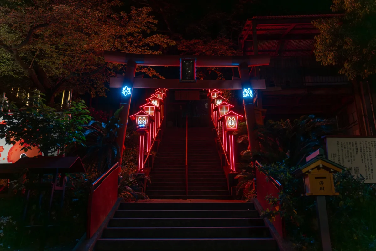 Marc · 26/04/2025 · 7008 x 4672 Cette photographie montre un **sanctuaire japonais illuminé la nuit**. Le **sujet principal** est l’escalier menant à une torii et au bâtiment sacré, encadré par des lanternes rouges.La **composition** est symétrique, avec une perspective ascendante. Le **cadrage** est serré, mettant en valeur les détails architecturaux et les jeux de lumière.Les **couleurs dominantes** sont le rouge des lanternes et le noir de la nuit, rehaussés par des éclairages bleutés. L’ambiance est **sereine et mystique**, renforcée par les ombres et la lumière tamisée. Le style évoque une **esthétique traditionnelle japonaise**, presque onirique.