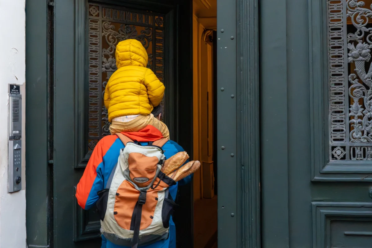 Marc · 30/11/2025 · 6658 x 4439 Cette photographie met en scène un enfant vêtu d’un manteau jaune et d’un sac à dos coloré, partiellement caché derrière une porte en métal ouvragée. Le cadrage est serré, centré sur le haut du corps de l’enfant, créant un effet de mystère.La lumière semble naturelle, douce, et met en valeur les couleurs vives du manteau et du sac. Les tons dominants sont les jaunes, bleus et bruns, contrastant avec le noir de la porte. Le style est documentaire et spontané, évoquant une ambiance quotidienne et chaleureuse, presque intimiste.