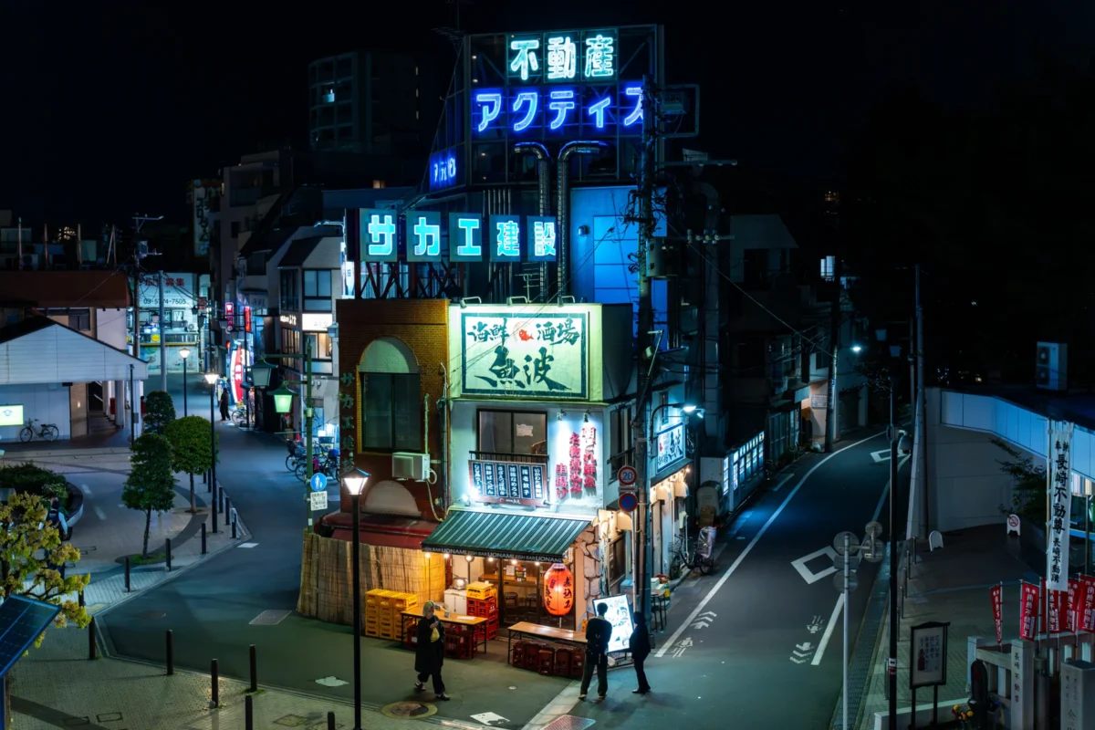 Marc · 16/04/2025 · 6705 x 4470 Cette photographie capture une rue animée la nuit dans une ville japonaise, probablement à Akihabara. Le sujet principal est l'intersection éclairée par des enseignes lumineuses colorées.La composition met en valeur les néons et les bâtiments aux styles variés. Le cadrage est large, incluant des éléments architecturaux et des passants. Les lumières vives, bleues, vertes et rouges dominent, créant une ambiance dynamique et futuriste. L'éclairage artificiel contraste avec l'obscurité nocturne, renforçant l'atmosphère électrique et vibrante typique des quartiers urbains japonais la nuit.