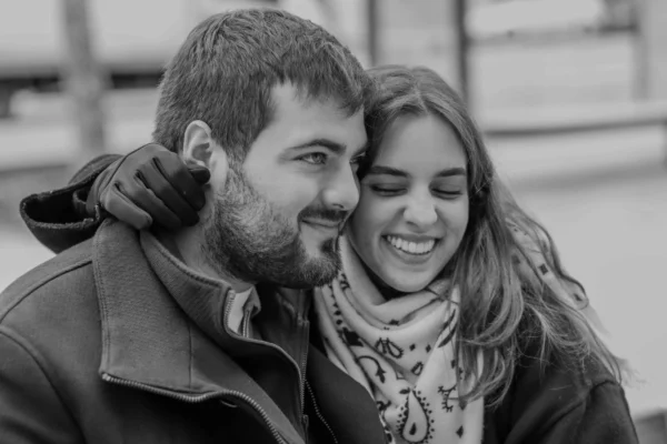Vera · 6127 x 4085 Cette photographie en noir et blanc met en scène un couple comme sujet principal, partageant un moment complice et souriant. La composition est serrée, centrée sur leurs visages et épaules, créant une intimité. Le cadrage est rapproché, mettant l'accent sur leur connexion.La lumière douce et naturelle adoucit les traits, avec des contrastes modérés. Les couleurs dominantes, bien que monochromes, varient du noir au gris clair, accentuant les textures des vêtements et des visages.Le style est simple et naturel, évoquant une ambiance chaleureuse et romantique, presque nostalgique.