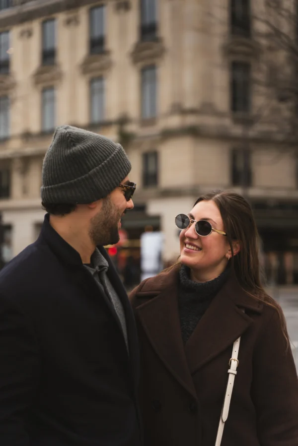 Juan · 14/02/2026 · 5304 x 7952 Cette photographie met en scène deux personnes en interaction dans un cadre urbain. Le sujet principal est un couple en plan serré, avec une composition centrée sur leurs visages et expressions. Le cadrage est serré, capturant leurs épaules et le haut du corps.La lumière est douce et naturelle, probablement en fin de journée, créant des ombres légères. Les couleurs dominantes sont les tons neutres : gris, marron et noir, avec des détails plus clairs sur les vêtements.Le style est réaliste et spontané, évoquant une ambiance intime et chaleureuse dans un environnement citadin.