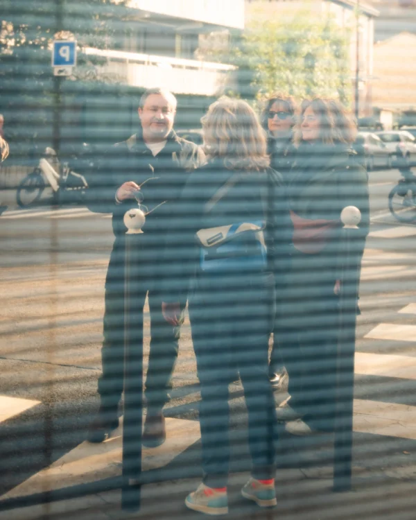 Alice · 21/02/2026 · 2838 x 3547 Cette photographie montre trois personnes vues à travers une vitre striée, créant un effet de distorsion. Le sujet principal semble être un adulte et deux enfants, probablement une famille.La composition est simple et naturelle, avec un cadrage serré sur les silhouettes. La lumière est tamisée, donnant une ambiance douce et légèrement mélancolique. Les couleurs dominantes sont des tons neutres et froids, avec des touches de bleu et de gris.Le style est documentaire et spontané, évoquant une scène de vie quotidienne. L’ambiance est intime et un peu nostalgique.