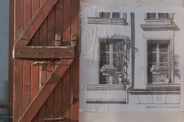 Dominique · 1000 x 667 Cette photographie montre un contraste entre deux éléments architecturaux. À gauche, une porte en bois rouillé et vieilli, avec une serrure et une poignée métalliques usées. À droite, une fenêtre stylisée en noir et blanc, représentant une décoration florale et des détails architecturaux.La composition juxtapose le réalisme brut de la porte et l'illustration graphique de la fenêtre. Le cadrage est serré, mettant en valeur les textures et détails. Les couleurs dominantes sont les tons rouillés et gris, avec des touches de bleu et de blanc. L’ambiance est à la fois mélancolique et artistique, évoquant le passage du temps et l’esthétique urbaine.
