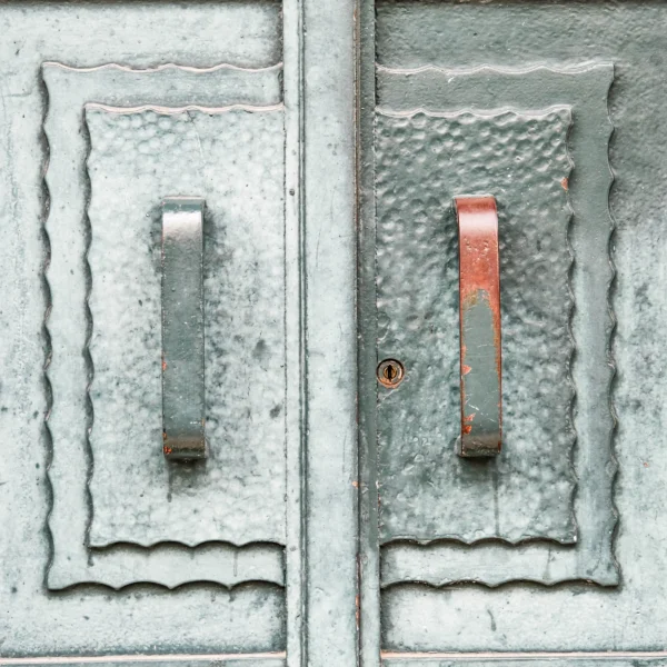 Nathalie F. · 21/02/2026 · 4160 x 4160 Cette photographie montre deux serrures anciennes sur une porte métallique rouillée. Le sujet principal est la comparaison entre une serrure intacte et une autre partiellement rouillée avec une clé insérée.La composition est symétrique, mettant en valeur les détails des serrures. Le cadrage est serré, centré sur les éléments métalliques. La lumière semble naturelle, mettant en relief les textures et les dégradés de rouille.Les couleurs dominantes sont les tons gris-bleutés de la rouille et du métal, avec une touche de rouge sur la clé. Le style est documentaire et réaliste, créant une ambiance à la fois rustique et mélancolique.