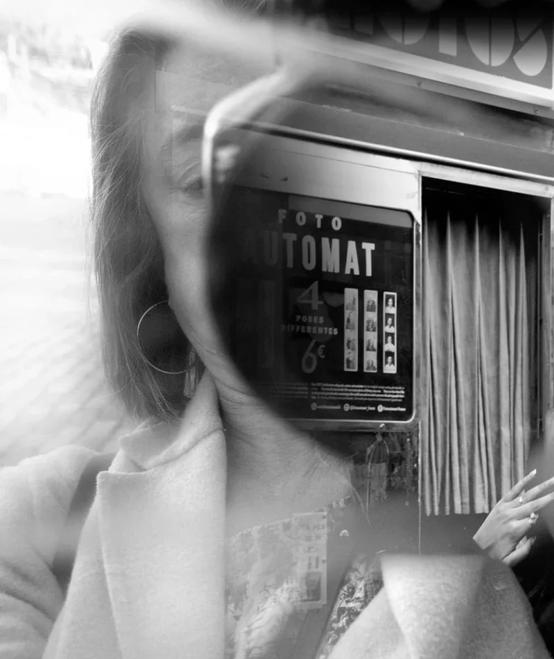 Pascale · 21/03/2026 · 840 x 1000 Cette photographie met en scène une personne tenant une **Polaroid instantanée** devant son visage, obscurcissant partiellement son identité. Le **sujet principal** est ce cliché, marqué "FOTO TOMAT". La **composition** joue sur la superposition et le flou, créant un effet mystérieux. Le **cadrage** est serré, centré sur le visage et l'objet.La **lumière** est douce, avec des contrastes modérés. Les **couleurs dominantes** sont en noir et blanc, renforçant l'aspect rétro et intemporel. Le **style** rappelle les photos argentiques des années 1970-80. L'**ambiance** est à la fois nostalgique et intrigante, mêlant intimité et jeu visuel.