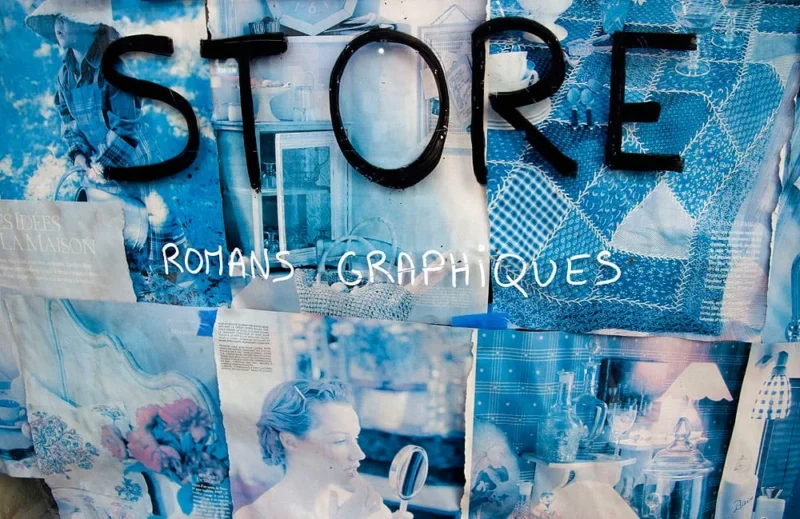Pascale · 21/03/2026 · 1000 x 649 Cette photographie montre une vitrine ou un panneau d’un **store** spécialisé en **romans graphiques**. Le sujet principal est le mot "STORE" écrit en gros caractères noirs, avec "ROMAN GRAPHIQUES" en dessous.La composition est dynamique, avec des images de couvertures de livres en arrière-plan, partiellement visibles. Le cadrage est serré, centré sur le texte et les illustrations. La lumière semble naturelle, éclairant uniformément la scène. Les couleurs dominantes sont les **tons bleus et blancs**, créant une ambiance moderne et épurée. Le style est épuré et visuellement attrayant, évoquant un espace culturel et artistique.