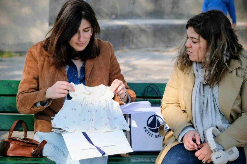 Denis · 22/03/2026 · 4714 x 3142 Cette photographie montre deux femmes assises sur un banc, étudiant des documents. Le sujet principal est leur interaction attentive autour des papiers.La composition est symétrique et naturelle, avec un cadrage serré sur elles. La lumière est douce et naturelle, probablement en extérieur par temps clair. Les couleurs dominantes sont les tons neutres (beige, gris) et les teintes chaudes des vêtements (marron, bleu).Le style est réaliste et quotidien, évoquant une ambiance studieuse et détendue.
