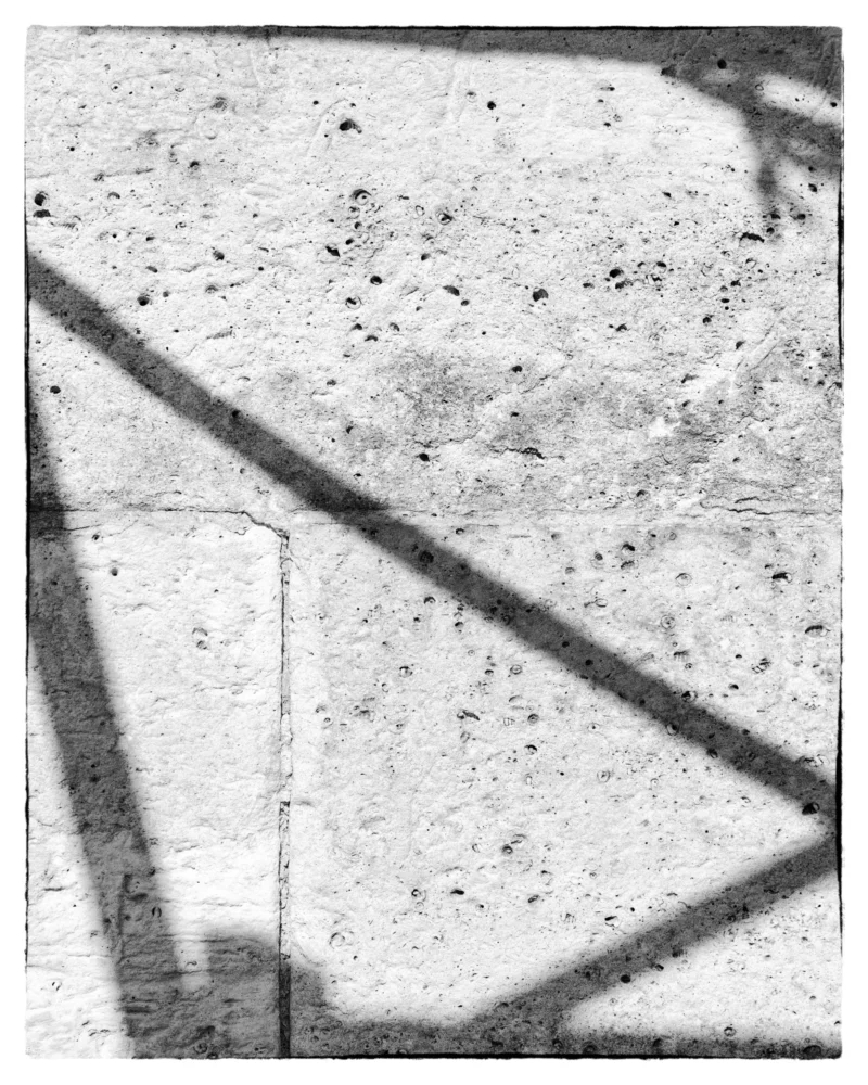 Thierry · 15/03/2026 · 3072 x 3840 Cette photographie en noir et blanc montre principalement une surface texturée et fissurée, probablement du béton ou un mur en pierre.La composition est géométrique, avec des lignes diagonales formées par des éléments architecturaux, comme des poutres ou des structures métalliques. Le cadrage est serré, mettant en valeur ces détails.La lumière semble naturelle, créant des contrastes marqués et des ombres nettes. Les couleurs dominantes sont les nuances de gris, renforçant l’aspect brut et industriel. Le style est épuré et documentaire, évoquant une ambiance froide et minimaliste, presque abstraite.