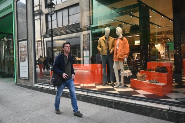 Mary P · 07/03/2026 · 5568 x 3712 Cette photographie montre un homme marchant devant une vitrine de magasin. Le sujet principal est cet homme, vêtu d’un manteau et portant un sac.La composition met en valeur la vitrine avec des mannequins habillés de vêtements colorés et des accessoires. Le cadrage est serré sur la scène urbaine, avec des éléments architecturaux en arrière-plan.La lumière est naturelle, légèrement tamisée, créant des ombres douces. Les couleurs dominantes sont les tons neutres (gris, bleu) avec des éclats de rouge et orange dans la vitrine.L’ambiance est urbaine et dynamique, reflétant une journée ordinaire en ville.