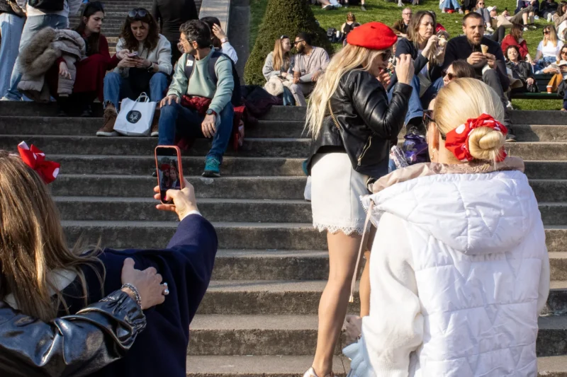 Loubna · 2048 x 1365 Cette photographie capture une scène festive en extérieur. Le **sujet principal** semble être une personne déguisée en personnage blanc et rouge, probablement pour une fête ou un carnaval. La **composition** montre plusieurs personnes en arrière-plan, dont certaines prennent des photos.Le **cadrage** est serré sur les personnages de l’avant, avec une profondeur de champ limitée. La **lumière** est naturelle, probablement en journée, avec des ombres douces. Les **couleurs dominantes** sont vives : rouge, blanc et des tons pastel, renforçant l’ambiance joyeuse.Le **style** est documentaire et spontané, reflétant une **ambiance** festive et conviviale.