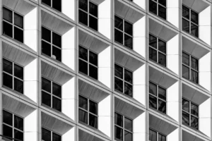 Yvon · 28/03/2026 · 6070 x 4046 Cette photographie met en scène la façade d’un immeuble moderne. Le sujet principal est la répétition géométrique des fenêtres et balcons en béton et métal.La composition repose sur un cadrage serré, soulignant les lignes horizontales et verticales, créant un effet rythmé et structuré. La lumière, naturelle et uniforme, accentue les contrastes en noir et blanc, renforçant les textures et ombres.Les couleurs dominantes sont le noir et le blanc, donnant un style épuré et contemporain. L’ambiance est à la fois froide et minimaliste, évoquant une architecture urbaine et industrielle.