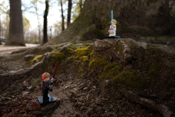 Juan MEDINA MARTINEZ · 7579 x 5055 Cette photographie met en scène deux figurines Lego posées sur un rocher moussus en extérieur. Le sujet principal semble être un personnage en tenue de randonneur, avec un autre personnage en arrière-plan, probablement un bonhomme de neige.La composition joue sur les contrastes entre les éléments naturels et les figurines miniatures. Le cadrage est serré, mettant en valeur les détails des figurines et du rocher. La lumière est douce, naturelle, avec des ombres marquées, créant une ambiance tamisée.Les couleurs dominantes sont les verts de la mousse et des arbres, les tons froids du rocher, et les couleurs vives des figurines. Le style est réaliste et photographique, avec une touche de fantaisie. L’ambiance est calme et presque poétique.