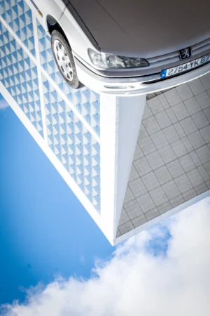AnJo · 28/03/2026 · 2823 x 4234 Cette photographie met en scène un angle architectural d’un bâtiment moderne. Le sujet principal est la jonction entre deux structures en surplomb, avec des motifs géométriques en damier et des lignes épurées.Le cadrage est serré, accentuant la perspective verticale et créant un effet dynamique. La lumière naturelle, vive et contrastée, souligne les contours nets et les jeux d’ombres. Les couleurs dominantes sont le blanc, le bleu clair du ciel et les touches de gris métallique.Le style est minimaliste et contemporain, évoquant une ambiance à la fois futuriste et élégante.