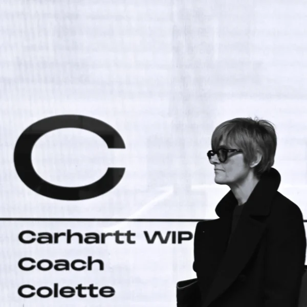 Pierre · 2320 x 2320 Cette photographie met en scène une personne au premier plan, en profil, vêtue d’un manteau sombre et portant des lunettes. L’arrière-plan montre un fond blanc avec un grand logo "C" et des noms de marques (Carhartt WIP, Coach, Colette).Le cadrage est serré sur le visage, créant un contraste entre le sujet et le fond. La lumière est douce et uniforme, sans ombres marquées. Les couleurs dominantes sont le noir et blanc, avec des touches de gris. Le style est épuré et minimaliste, évoquant une ambiance sophistiquée et moderne, presque intemporelle.