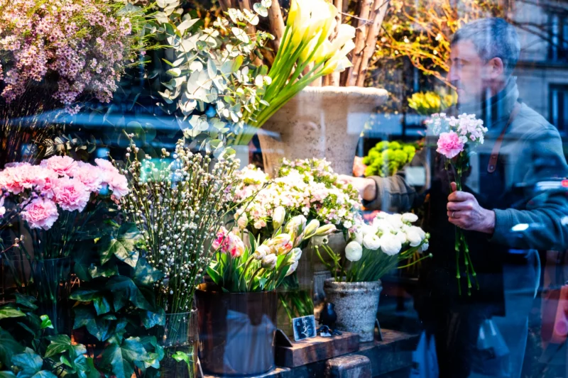 Jean-Marc · 21/03/2026 · 5771 x 3847 Cette photographie met en scène un **marché de fleurs**. Le **sujet principal** est une variété de bouquets et de plantes disposés dans des pots et des paniers. La **composition** est dynamique, avec des éléments superposés et un léger flou d’arrière-plan.Le **cadrage** est serré, centré sur les fleurs, tandis que la **lumière** naturelle, douce, met en valeur les teintes. Les **couleurs dominantes** sont des tons pastel (rose, blanc, vert) et quelques touches vives.Le **style** est réaliste et spontané, évoquant une ambiance **vivante et chaleureuse**, typique d’un marché artisanal.