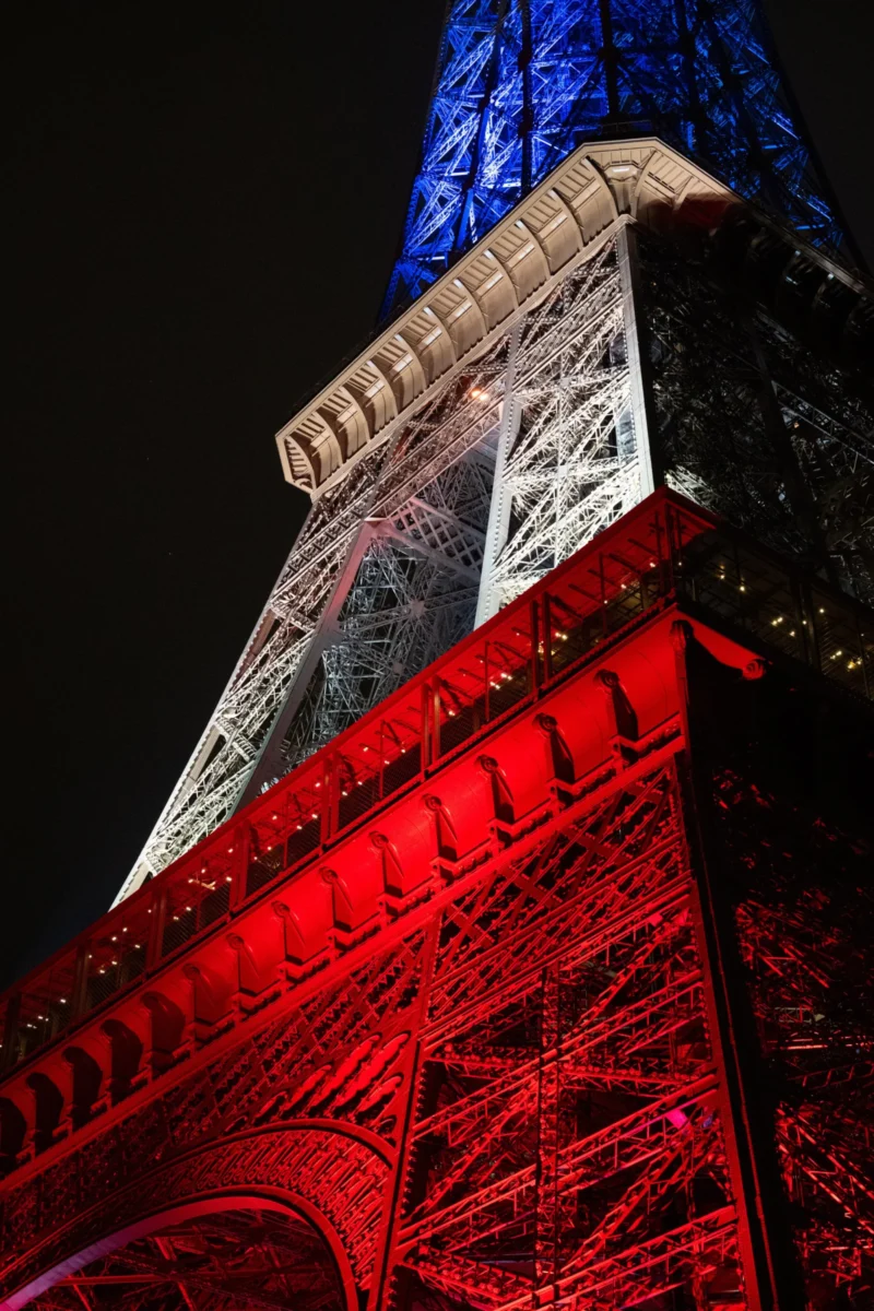 Daniel · 3753 x 5629 Cette photographie montre la partie supérieure de la Tour Eiffel. Le sujet principal est la structure métallique illuminée. La composition met en valeur le cadrage serré sur la tour, accentuant ses détails architecturaux.Les lumières, principalement bleues et rouges, créent un jeu de contrastes saisissants. Les couleurs dominantes sont le bleu électrique en haut et le rouge intense en bas, avec des teintes métalliques grises.Le style est épuré et moderne, mettant en avant l'éclairage nocturne. L’ambiance est à la fois mystérieuse et festive, soulignant la beauté monumentale et lumineuse de la tour.