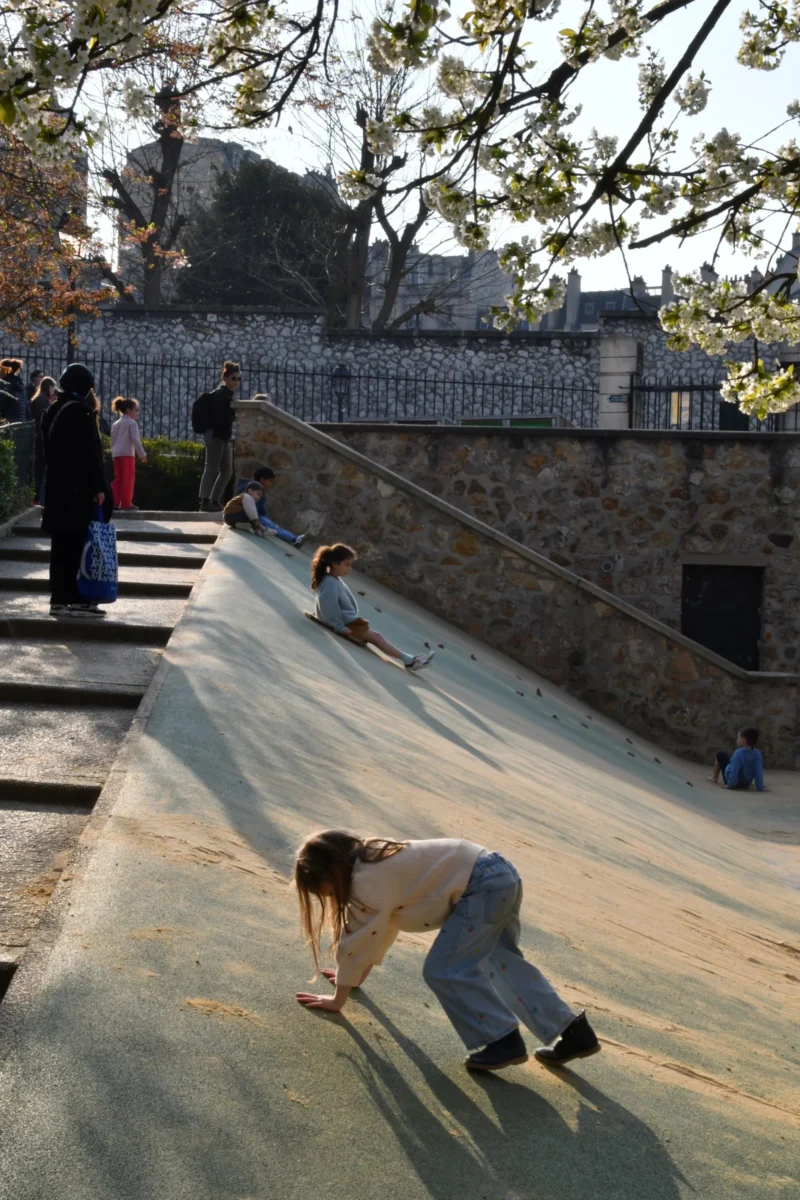 Vincent · 21/03/2026 · 3712 x 5568 Cette photographie montre deux enfants jouant sur une surface inclinée et lisse, probablement en plastique ou métal. Le sujet principal est l’enfant en bas, en position penchée, tandis que l’autre glisse derrière lui.La composition met en valeur un cadrage dynamique, avec une perspective basse. La lumière est naturelle, vive et légèrement rasante, créant des ombres marquées. Les couleurs dominantes sont les tons froids (bleu du ciel, gris de la surface) et les couleurs chaudes (vêtements des enfants).Le style est documentaire et spontané, capturant un moment ludique et insouciant, dans une ambiance joyeuse et estivale.