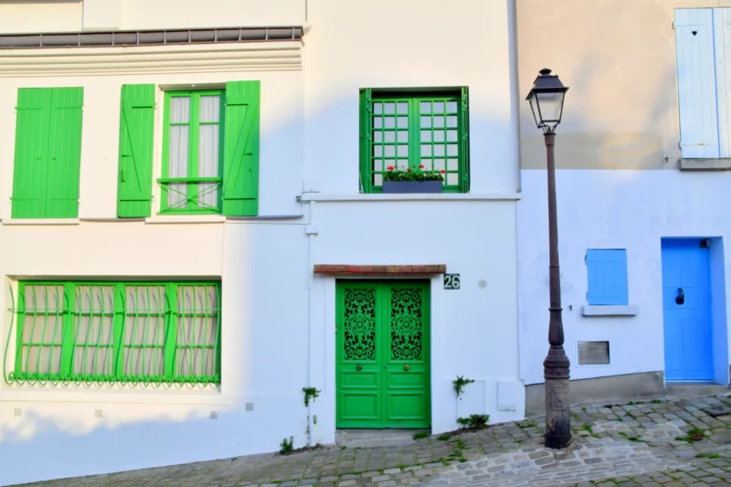 Vincent · 21/03/2026 · 5568 x 3712 Cette photographie montre une façade de maison aux **couleurs vives**. Le **sujet principal** est la porte et les fenêtres vertes, contrastant avec le mur blanc et les encadrements bleus.La **composition** est symétrique, avec un **cadrage serré** sur la partie basse du bâtiment. La **lumière** naturelle, douce, met en valeur les teintes sans ombre marquée. Les **couleurs dominantes** sont le blanc, le vert et le bleu, créant une ambiance **provençale et chaleureuse**. Le style est **épuré et traditionnel**, évoquant un charme rural ou méditerranéen. L’**ambiance** est paisible et accueillante.