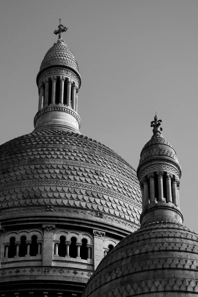 Daniel · 21/03/2026 · 3107 x 4661 Cette photographie met en scène deux dômes de style architectural religieux, probablement orthodoxe. Le sujet principal est ces structures ornées de tuiles et de croix en haut.La composition est symétrique, avec un cadrage serré qui isole les dômes. La lumière, douce et uniforme, crée des contrastes nets entre les formes et les ombres, accentuant les détails. En noir et blanc, les couleurs dominantes sont absentes, mais les nuances de gris renforcent la texture et la profondeur.Le style est classique et monumental, évoquant une ambiance solennelle et intemporelle.