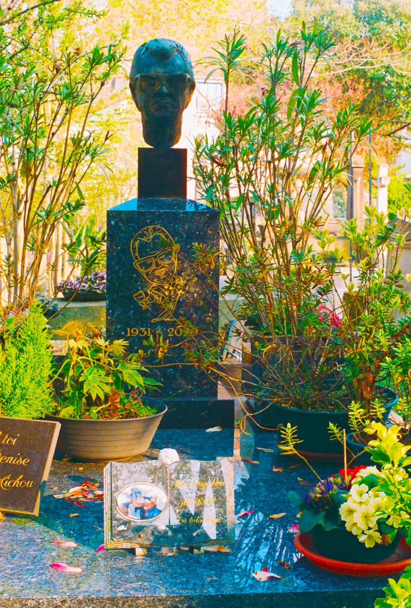 Nadia · 2433 x 3601 Cette photographie met en scène un **buste en pied** comme sujet principal, posé sur un socle orné de motifs.La **composition** est symétrique, avec des plantes et fleurs disposées autour. Le **cadrage** est serré, centré sur le buste et son environnement immédiat.La **lumière** est douce et naturelle, créant des ombres légères. Les **couleurs dominantes** sont des tons verts, bleus et dorés, avec des touches de rouge et de blanc.Le style évoque une **ambiance paisible et respectueuse**, presque sacrée, renforcée par les éléments végétaux et l’eau en mouvement.