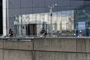 Cyrille · 28/03/2026 · 2026 x 1351 Cette photographie montre des personnes assises sur une balustrade devant un bâtiment moderne aux façades vitrées réfléchissantes. Le sujet principal semble être ces individus, dont les silhouettes sont reflétées dans les vitres.La composition est équilibrée, avec un cadrage serré sur le premier plan et un arrière-plan architectural. La lumière est naturelle, légèrement diffuse, créant des contrastes doux. Les couleurs dominantes sont les tons gris (bâtiment, balustrade) et bleutés (reflets), avec des touches de noir et blanc pour les vêtements.Le style est réaliste et contemporain, évoquant une ambiance urbaine calme et moderne.
