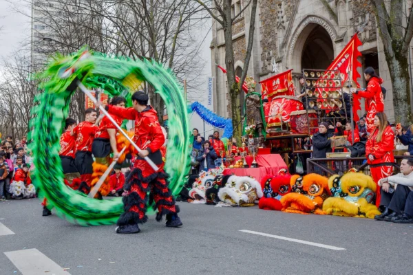 Frédéric · 2520 x 1680 Cette photographie capture une scène de défilé festif. Le **sujet principal** est un groupe de danseurs vêtus de costumes noirs et rouges, manipulant un grand cerceau vert lumineux. La **composition** montre aussi des chars décorés et des accessoires colorés (bouées, ballons).Le **cadrage** est serré sur les danseurs, avec une profondeur de champ qui inclut le décor en arrière-plan. La **lumière** semble naturelle, bien que renforcée pour mettre en valeur les couleurs vives. Les **couleurs dominantes** sont le vert éclatant, le rouge et le noir, créant un contraste dynamique.L’ambiance est **joyeuse et énergique**, typique d’une fête ou d’un carnaval. Le style est **vivant et théâtral**.