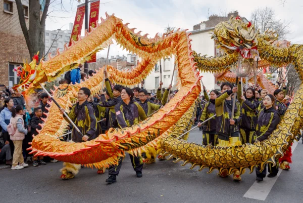 Frédéric · 2517 x 1680 Cette photographie capture une danse traditionnelle du **dragon chinois**, sujet principal emblématique de célébrations culturelles, probablement lors d’un festival comme le Nouvel An lunaire.La **composition** montre le dragon sinueux, porté par plusieurs danseurs, encadré par une foule en mouvement. Le **cadrage** est dynamique, centré sur le dragon, avec des spectateurs en arrière-plan. La **lumière** semble naturelle, bien que légèrement contrastée, mettant en valeur les détails dorés.Les **couleurs dominantes** sont le **doré**, le **rouge** et le **noir**, typiques des dragons festifs. Le style est **traditionnel et festif**, évoquant une **ambiance joyeuse et collective**, riche en symboles culturels.