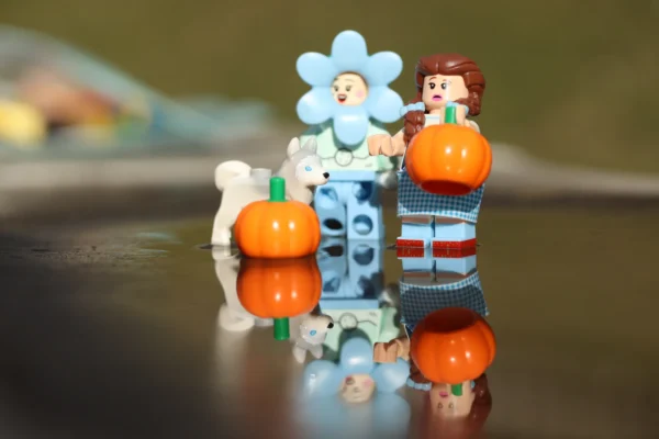 Françoise Mettais · 14/03/2026 · 6000 x 4000 Cette photographie met en scène des figurines en Lego représentant des personnages stylisés. Le sujet principal est une famille composée d’un adulte et d’un enfant, entourés d’éléments décoratifs comme une fleur et une citrouille.La composition est horizontale, avec un cadrage serré sur les figurines. La lumière douce et naturelle crée des ombres douces, adoucissant les contours. Les couleurs dominantes sont les tons bleus, blancs et oranges, apportant une ambiance joyeuse et ludique. Le style est épuré et minimaliste, évoquant une touche créative et enfantine. L’ambiance est chaleureuse et fantaisiste.