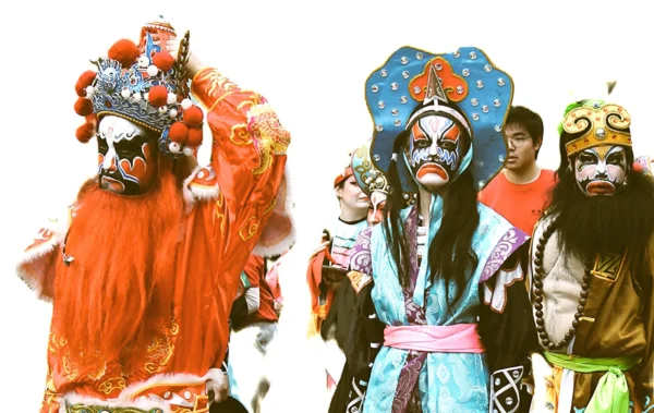 Sophie · 2499 x 1577 Cette photographie met en scène des personnages vêtus de costumes traditionnels colorés, probablement inspirés d’un théâtre ou d’une danse folklorique asiatique, comme l’opéra chinois.La composition montre trois figures principales en premier plan, avec des masques et des atours élaborés. Le cadrage est serré, mettant l’accent sur les détails des costumes et des expressions. Les couleurs dominantes sont vives : oranges, bleus, rouges et blancs, créant un contraste saisissant. La lumière semble artificielle, avec des ombres marquées, renforçant l’aspect dramatique. Le style évoque un mélange de tradition et de spectacle, dans une ambiance à la fois mystique et festive.