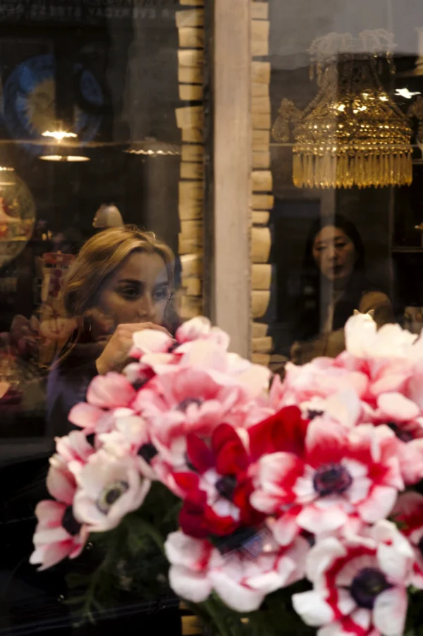 Thomas Ternisien · 07/03/2026 · 2048 x 3080 Cette photographie montre comme sujet principal un bouquet de fleurs (anémones blanches et roses) en premier plan, partiellement reflété dans une vitrine.La composition joue sur les reflets et les superpositions, avec une ambiance légèrement floue et mystérieuse. Le cadrage est serré sur les fleurs, mais inclut aussi des silhouettes et des lumières en arrière-plan.Les couleurs dominantes sont les tons blancs, roses et rouges des fleurs, contrastant avec les reflets dorés et les teintes chaudes de l'arrière-plan. Le style est artistique et poétique, évoquant une ambiance onirique et élégante.